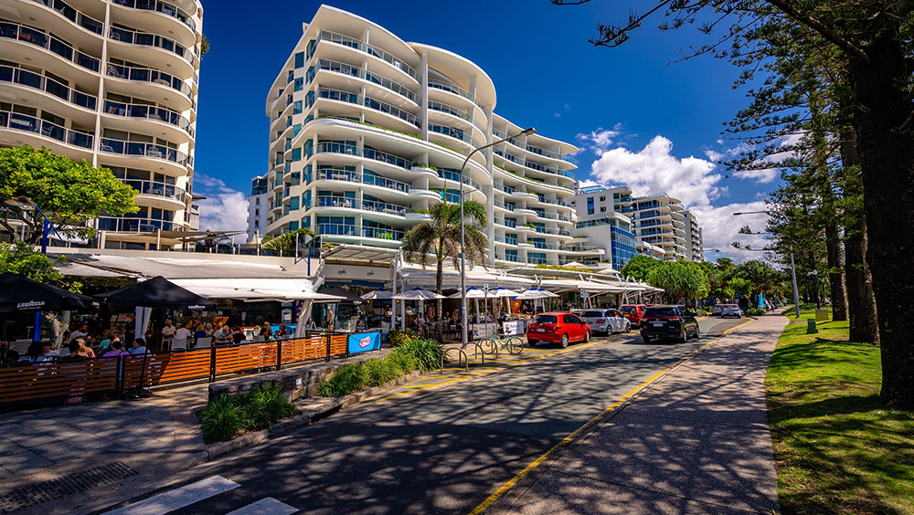 Apartment buildings along a palm-lined seaside esplanade