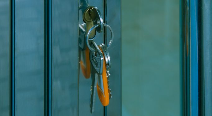 Key ring with orange label put in the keyhole of a frequently used metal and glass front door.